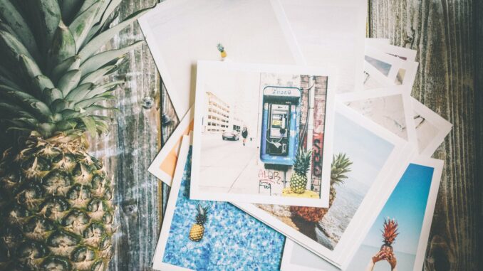 Assorted Photo Beside Pineapple on Top of Brown Surface