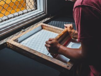 man holding printing screen near white window