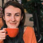 a woman holding a cup of coffee in front of her face