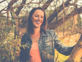 woman wearing blue denim jacket behind of tree