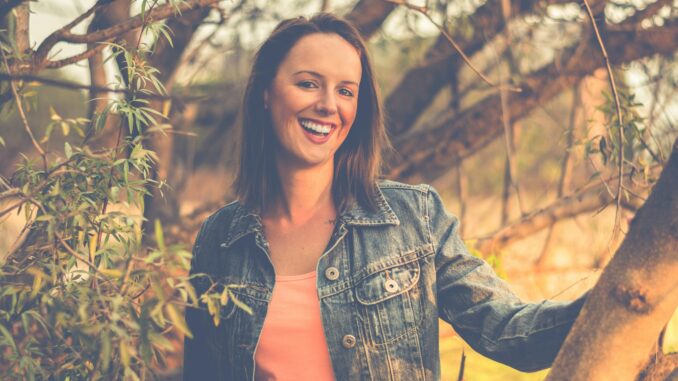 woman wearing blue denim jacket behind of tree